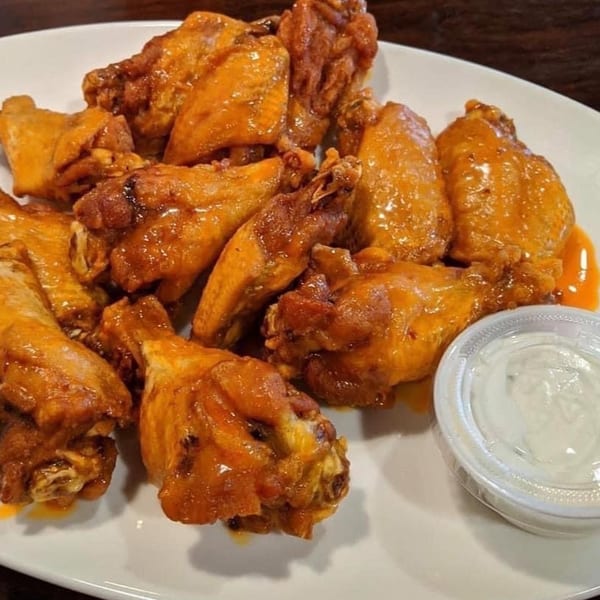 A white plate piled high with Patsy's Bar & Grill's buffalo wings and a side of ranch.