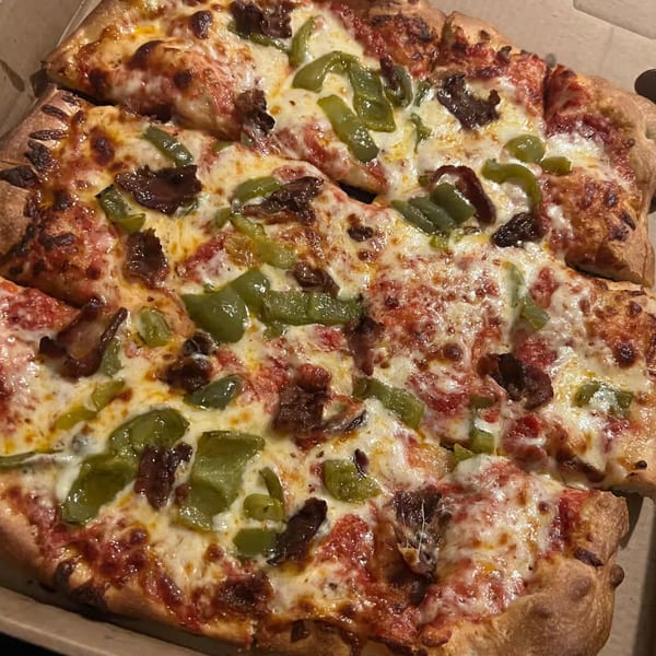 Close-up of a Patsy's Bar & Grill pizza with green peppers, meat, and melted cheese.